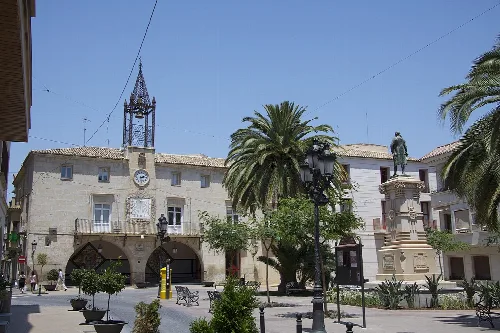 Plaza de España in Novelda with town hall, palm trees, and a central statue.