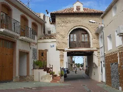 Entrance gate with stone arch and houses on the sides in Quinto, Zaragoza.