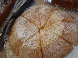 Sliced almond cake dusted with powdered sugar.