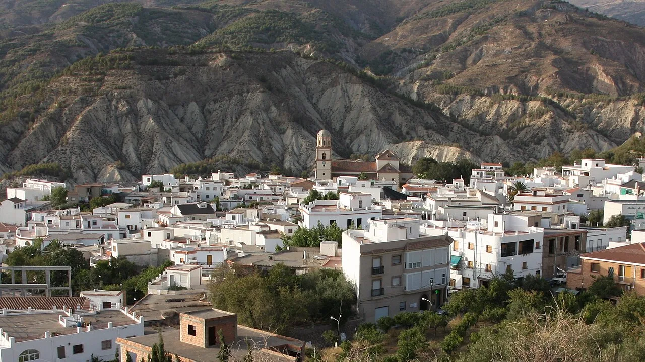 Städtische Landschaft mit weißen Häusern in Alcolea und Bergen im Hintergrund.