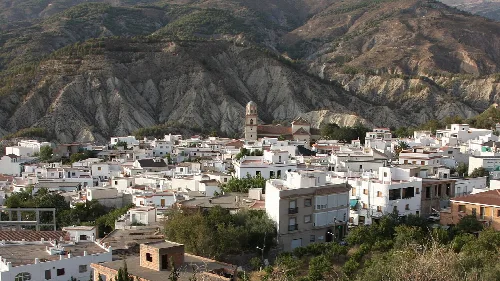 Paisaje urbano de casas blancas en Alcolea, con montañas de fondo.