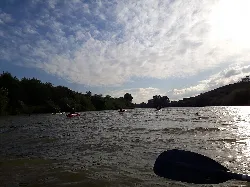 Kajaks auf dem Guadalquivir-Fluss mit bewölktem Himmel und Bäumen an den Seiten.