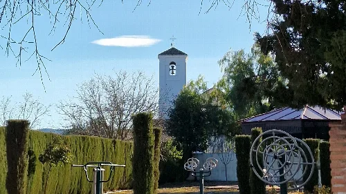 Kirche San Isidro Labrador in Ventas de Huelma mit Bäumen und Garten.