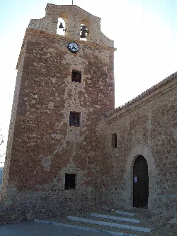 Stone tower with bell tower and clock at San Benito Church in Vícar.