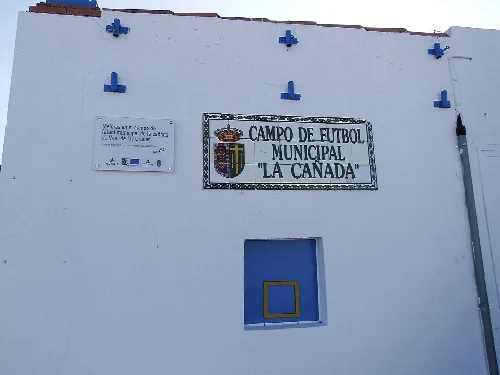 Facade of a football field with a sign and a small window.