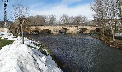 Steinbrücke über den Fluss Pisuerga mit Schnee an den Ufern.