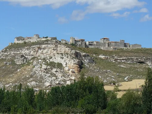 View of a village on a hilltop with castle and houses.