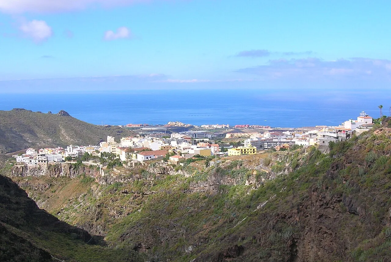 View of a town in a valley with the sea in the background.