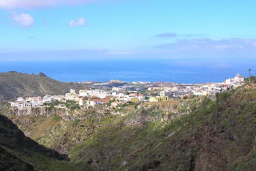 Vista de un pueblo en un valle con el mar al fondo.