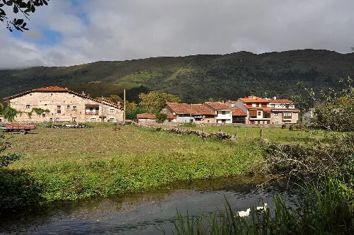 Río con casas y colinas verdes en Ruente, Cantabria.