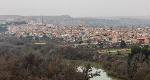 Panoramic view of a town with houses and hills in the background.