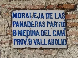Blue text ceramic plaque on brick wall.