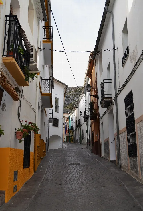 Street in Famorca with white houses and balconies with plants.