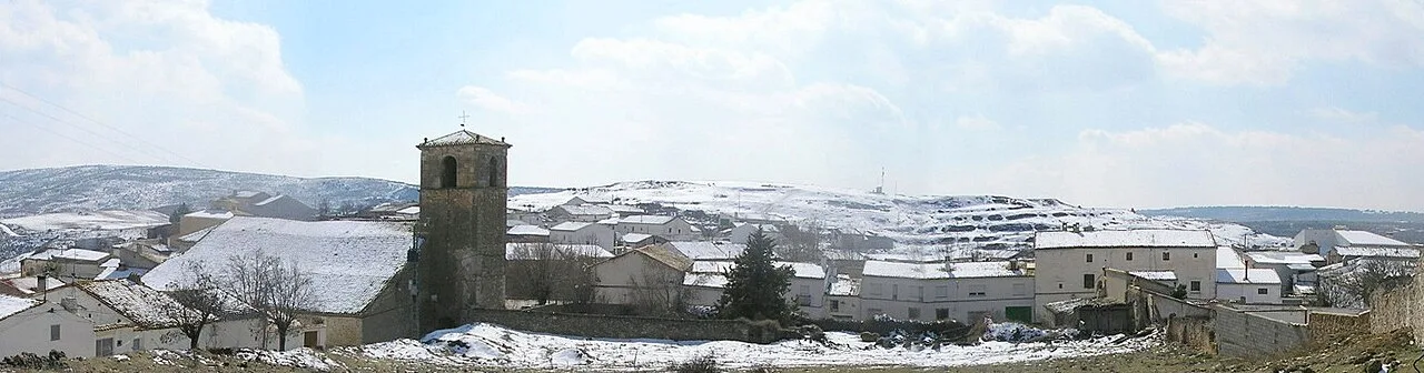 Landschaft mit Häusern und einem Turm in einem verschneiten Dorf.