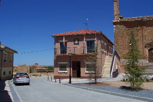 Edificio del Ayuntamiento con escaleras exteriores y bandera en Villamuriel de Campos.