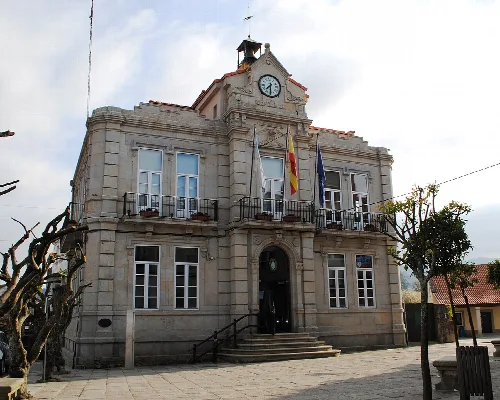 Steinernes Gebäude mit Uhr und Flaggen an der Fassade.