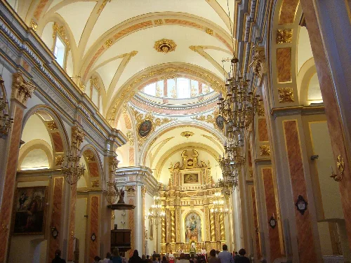 View of the interior of a church with a golden altar and decorated ceilings.