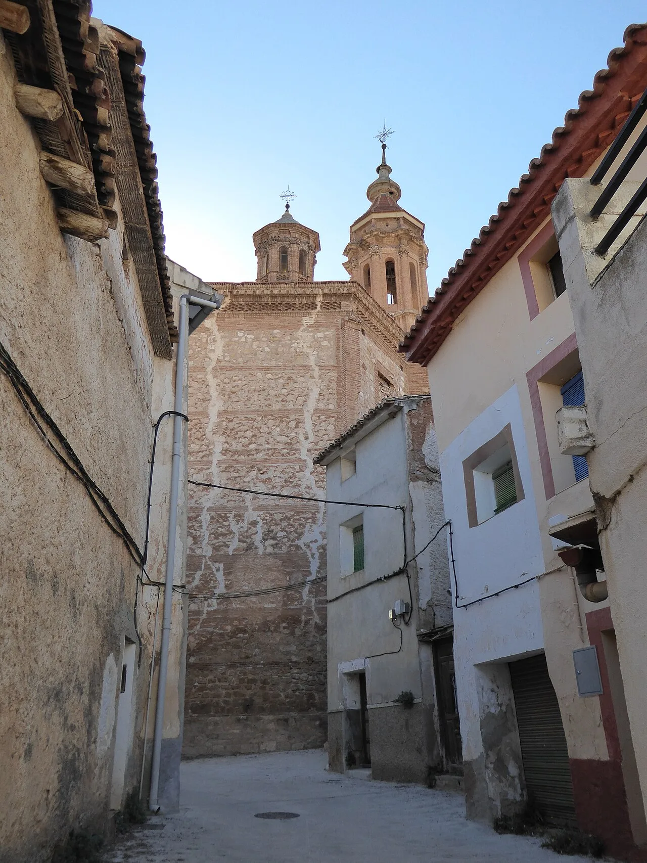 Enge Straße mit Gebäuden und einer Kirche im Hintergrund in Blesa