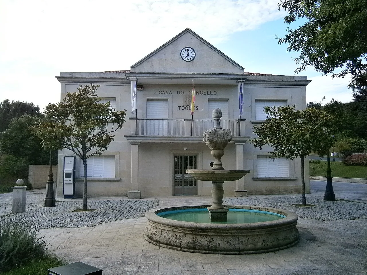 Rathaus von Toques mit Brunnen und Bäumen auf dem Platz.
