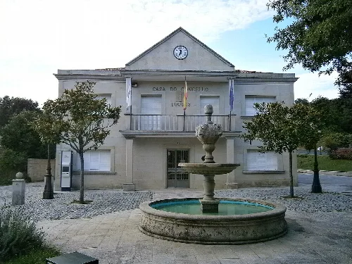 Rathaus von Toques mit Brunnen und Bäumen auf dem Platz.