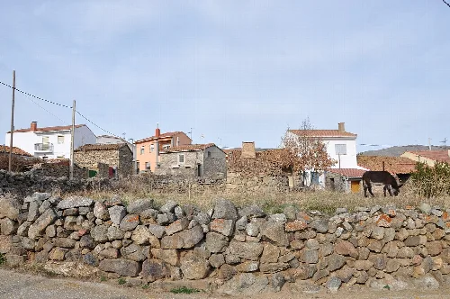 Häuser und ein Pferd auf einem Feld in Poveda, Ávila, Spanien.