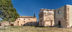 Ruins of Valldecrist Charterhouse in Altura, Castellón, with stone buildings and blue sky.