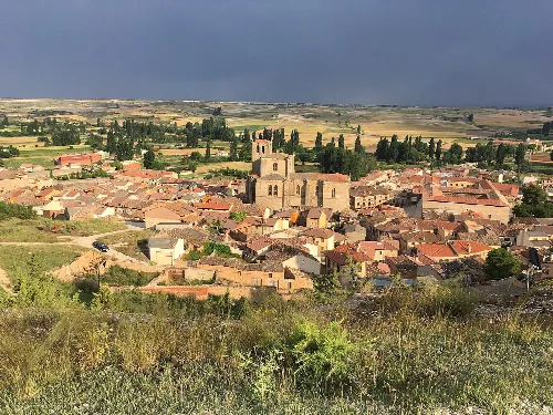 View of Peñaranda de Duero with church and houses in a rural landscape.