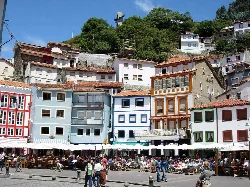 Colorful houses in Cudillero's port with tourists on the terrace.