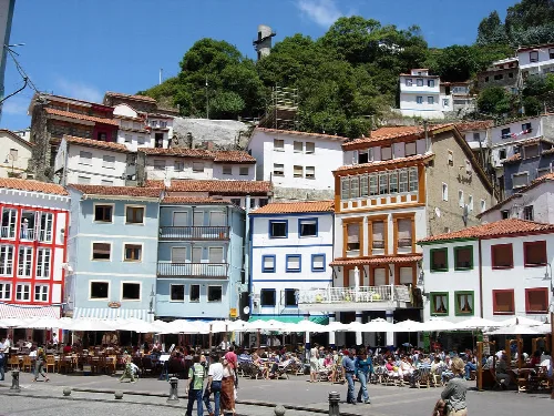 Casas coloridas en el puerto de Cudillero con turistas en la terraza.