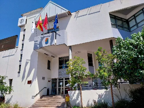 Weißes Gebäude mit Flaggen und Treppen am Eingang.