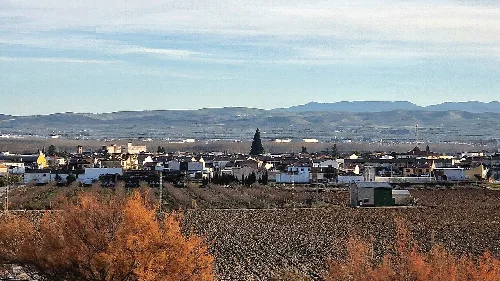 Ländliche Landschaft mit Häusern und Bergen im Hintergrund.