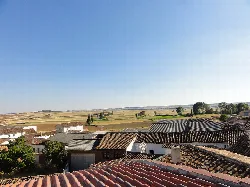 Felder und Dächer von Prádanos de Ojeda mit klarem blauen Himmel.