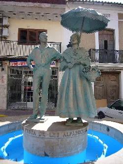 Escultura de una pareja con paraguas y cesta en una fuente en Bétera.