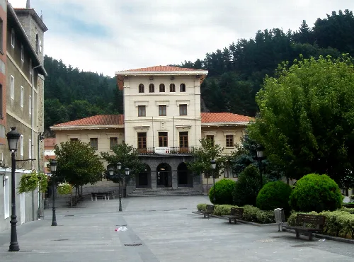 Edificio del ayuntamiento de Ugao en Vizcaya con árboles y bancos en la plaza