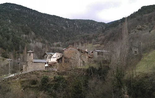 Blick auf ein Dorf an einem Hang mit Steinhäusern und Bäumen.