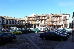 Plaza Mayor of La Puebla de Montalbán with buildings and parked cars.