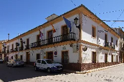 White building with balcony and flags on the facade of the town hall.