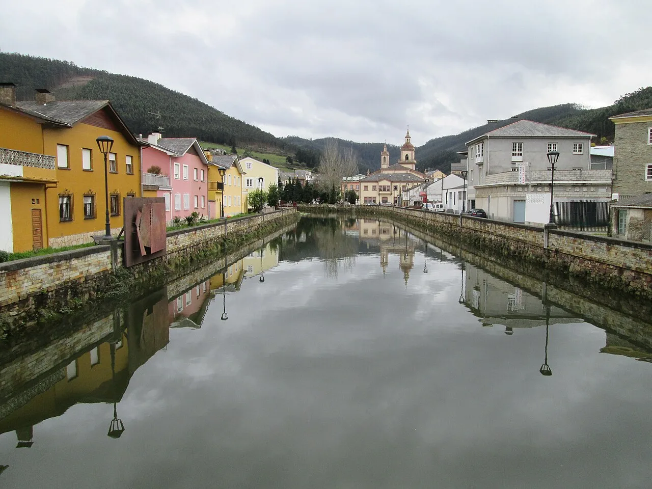 Suarón-Fluss mit bunten Häusern und bewölktem Himmel in Vegadeo.