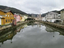 Suarón-Fluss mit bunten Häusern und bewölktem Himmel in Vegadeo.