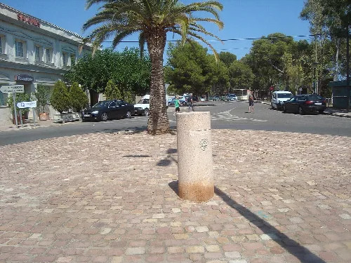 Calle con palmeras y coches en Almazora, con la Vía Augusta en el fondo.