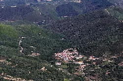 Vista aérea de un pueblo en un valle rodeado de montañas y vegetación.