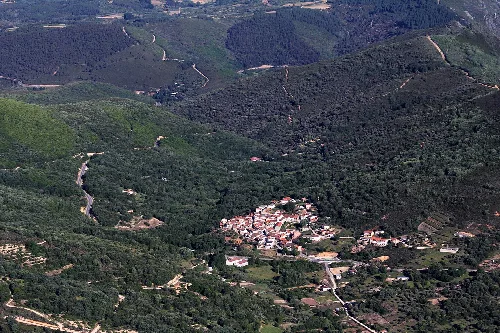 Vista aérea de un pueblo en un valle rodeado de montañas y vegetación.