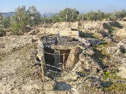 Megalithic stone tomb at an archaeological site with signs and fencing.