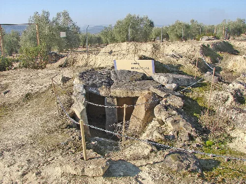 Megalithisches Steingrab auf einer archäologischen Stätte mit Schildern und Absperrung.