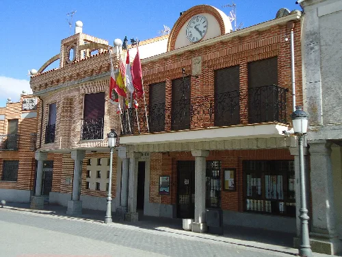 Edificio con fachada de ladrillo, banderas y reloj en la parte superior.