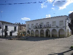 White building with arches on the ground floor and a balcony on the first floor.