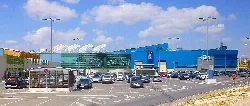 Einkaufszentrum mit blauer Struktur und vielen Autos auf dem Parkplatz.
