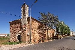 Kleine Kirche mit Glockenturm und Traktor auf der Straße in Campillo de Altobuey.