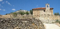 Small church with tower and stone wall in Corrales de Duero.
