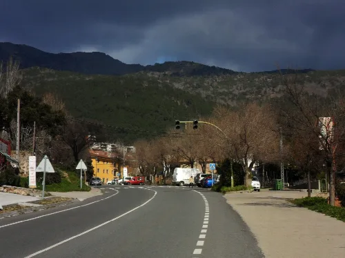 Blick auf die Hauptstraße von Piedralaves mit Bergen im Hintergrund und kahle Bäume.